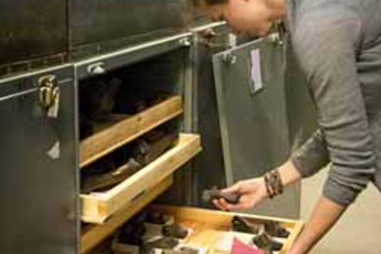 A female researcher grabs an artifact from an open drawer within a metal cabinet