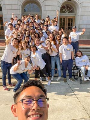 large group of people standing together and smiling, wearing CalDay t-shirts