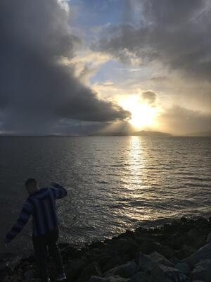 person balancing on rocks that border the ocean 