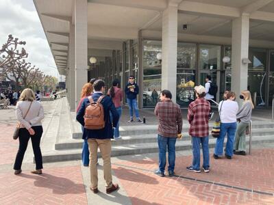 A group of individuals facing and listening to a campus ambassador during their tour of the UC Berkeley campus.