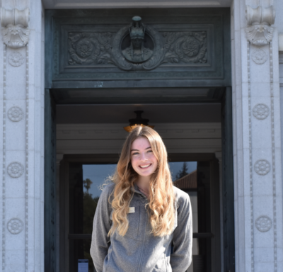 student wearing a grey sweatshirt in front of doe library 