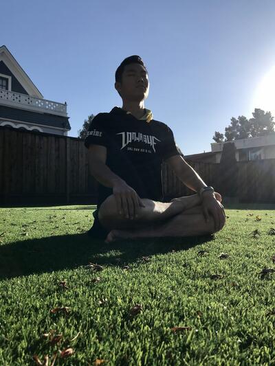 student meditating on the grass in a backyard